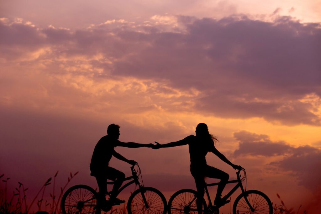 woman on bike reaching for man's hand behind her also on bike for easy date night