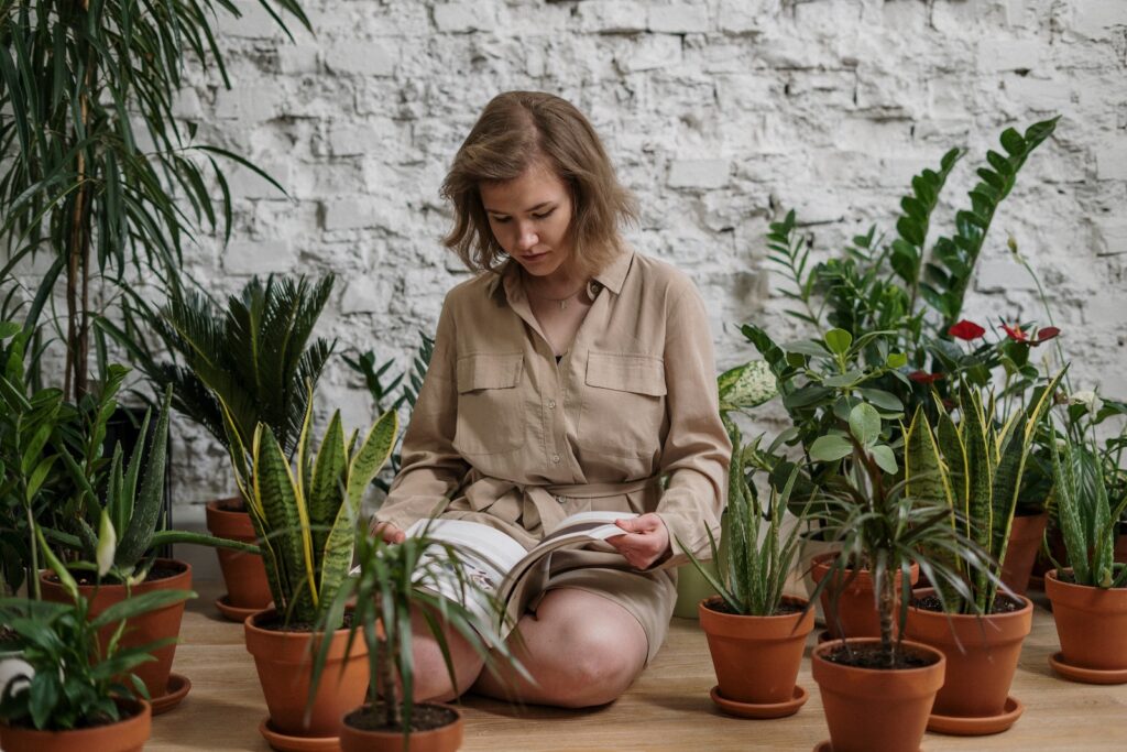 Woman Sitting While Reading Book Near Potted Plants in sustainable planters